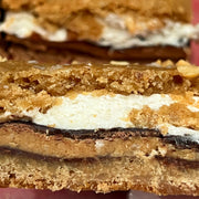 close up of layered cookie bar with marshmallow fluff, peanut butter cups, and graham cookie crust